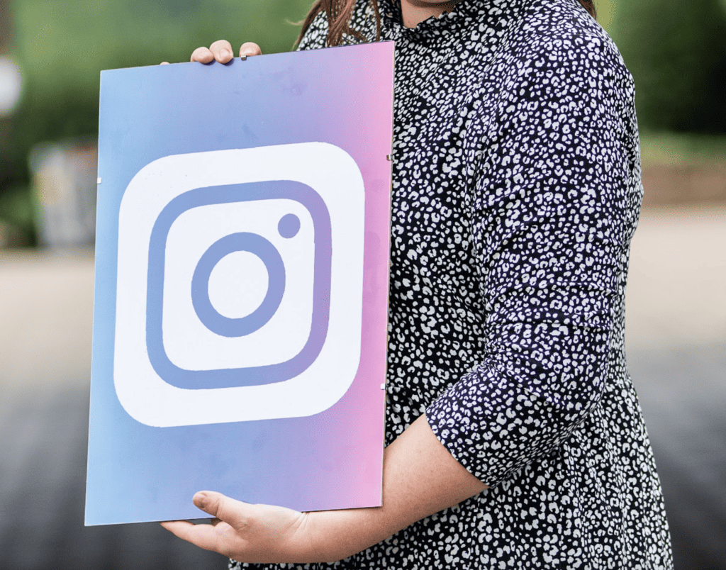 woman holding Instagram logo on a a gradient board